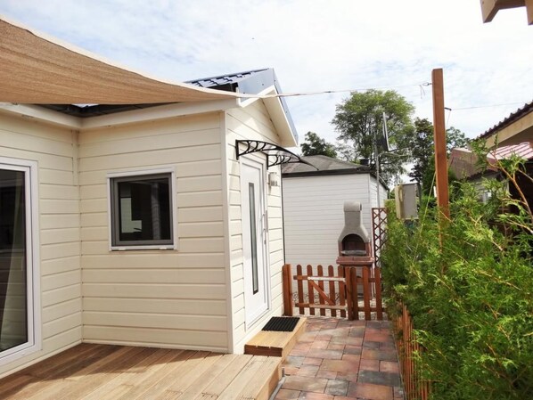 A residential property with a covered patio, a small brick pathway, and a wooden fence.