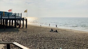 A beach with a pier, people walking, and flags. - Haus Jeff by Interhome (Wervershoof)