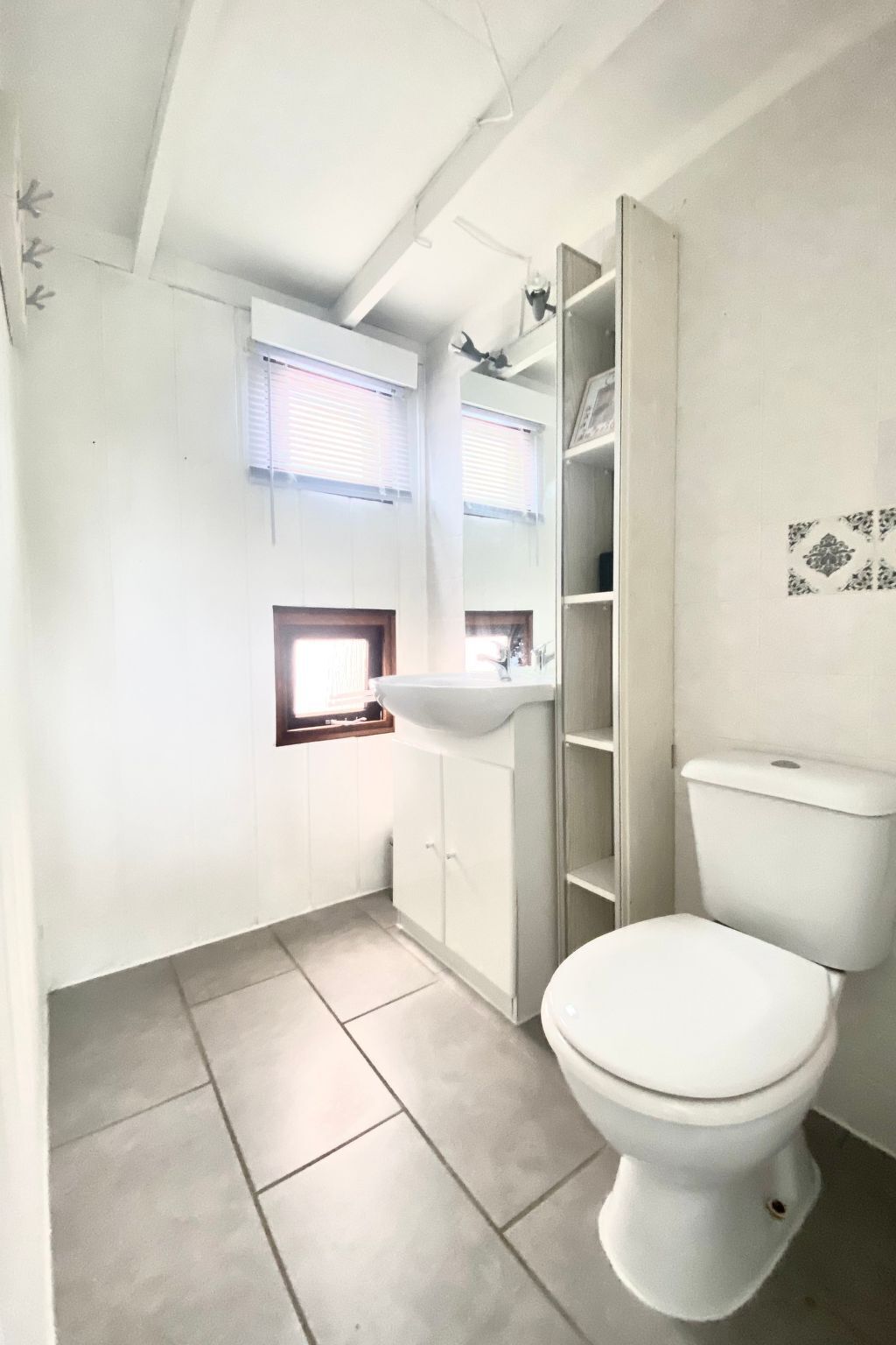 A small bathroom with a toilet, a sink, and a window.