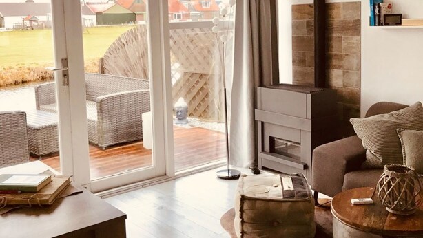A modern living room with a large sliding glass door leading to an outdoor area, a fireplace, and a cozy seating arrangement. - Vacation home  by Interhome (Wervershoof)