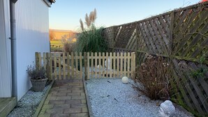 A garden pathway leading to a wooden gate, surrounded by gravel and plants. - Vacation home  by Interhome (Wervershoof)