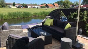 An outdoor seating area with wicker furniture, a table, and a large umbrella. - Vacation home  by Interhome (Wervershoof)