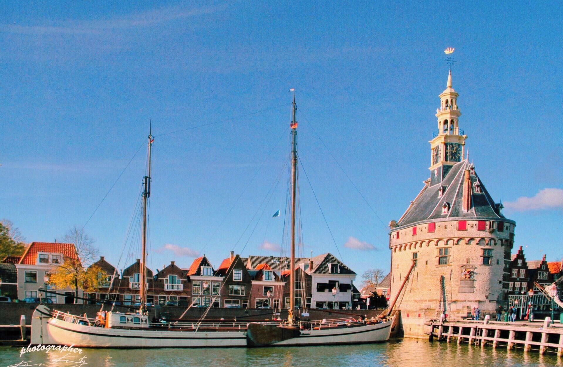 A historic building with a tower and a dock with boats.
