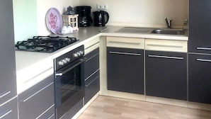 Een moderne keuken met zwarte kastjes, een gasfornuis, een oven, een magnetron en een koffiezetapparaat.