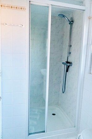 Eine begehbare Duschkabine mit Handbrause und am Wand montiertem Wasserhahn.
