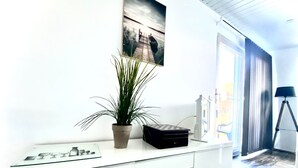 A modern living room with a white entertainment unit, a potted plant, and a framed picture on the wall.
