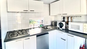 A kitchen with white cabinets, a gas stove, a microwave, and a toaster.