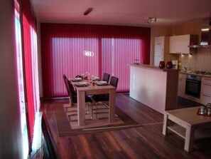 A compact kitchen with a dining area, wooden flooring, and a pink curtain backdrop. - Auszeit direkt am Wasser by Interhome (Wervershoof)