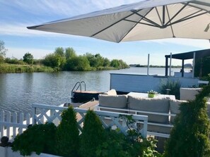 Une terrasse au bord de la rivière avec des sièges extérieurs, un quai pour bateaux et un espace abrité.