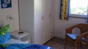 A bedroom with a bed, a wardrobe, a chair, and a window with curtains. - Haus Jule by Interhome (Wervershoof)