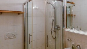 Ein modernes Badezimmer mit einer Duschkabine, einer weißen Toilette und einem Waschbecken mit Spiegel darüber.