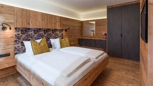 Un dormitorio moderno con cabecera de madera, un espejo grande, televisión y armario.