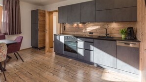 Una cocina moderna con armarios oscuros, encimera de madera y comedor con mesa y sillas.