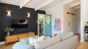 Una sala moderna con televisor de pantalla plana, consola de madera y sofá gris.
