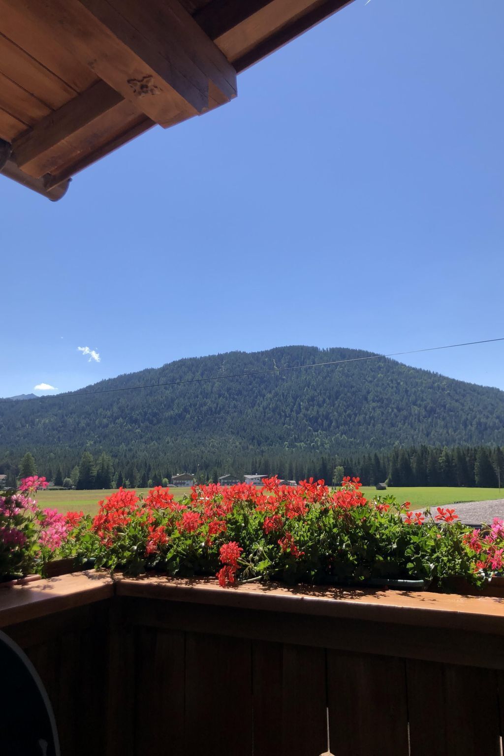 Ein Holzbalkon mit Blick auf einen Berg und ein Feld.