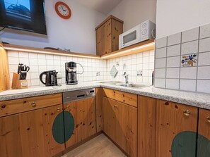A kitchen with wooden cabinets, a microwave, a coffee maker, and a sink.