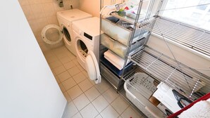 Ein Waschraum mit Waschmaschine, Trockner und Regalen mit gefalteten Handtüchern und Leintüchern.