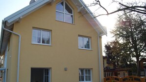 A two-story house with a yellow exterior, a covered patio with a table and chairs, and a wooden fence. - Florian 1 in Bezirk 21-Floridsdorf by Interhome (Vienna)