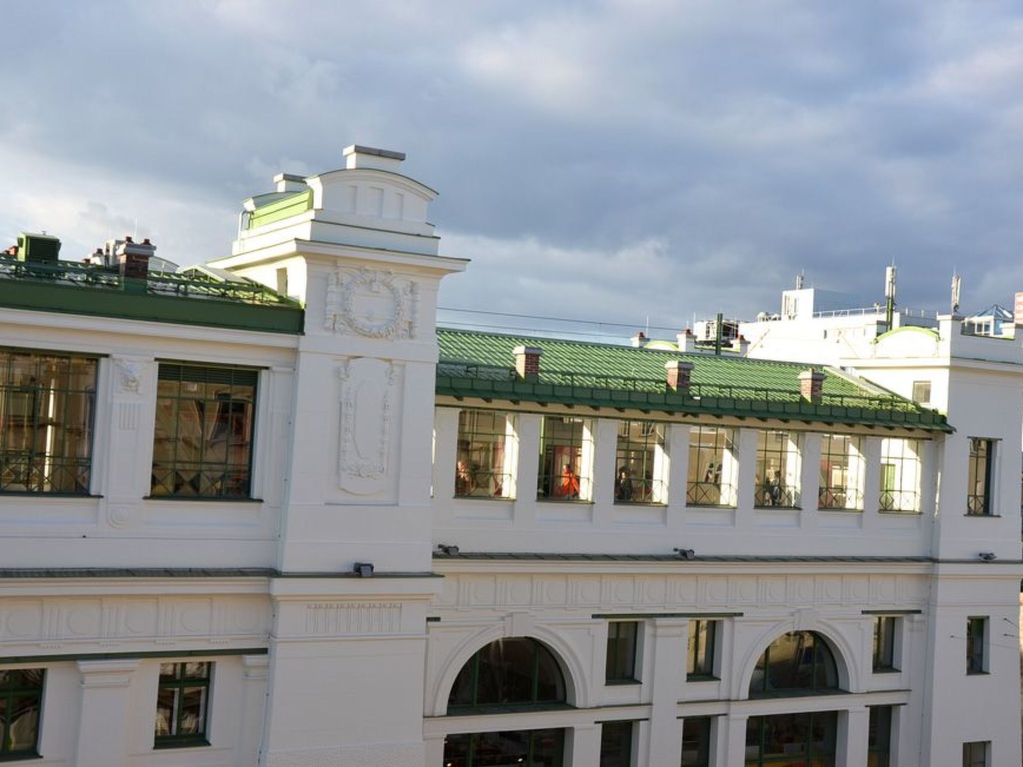 A white building with green roofs and large windows.