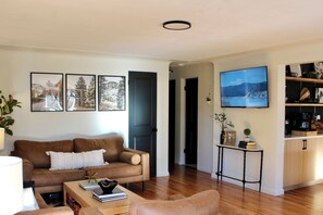 Ein Wohnzimmer mit einem braunen Sofa, einem Couchtisch und einem Fernseher an der Wand.