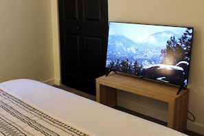 Ein Fernseher auf einem Holzboden in einem Zimmer mit einem Bett und einer Tür.