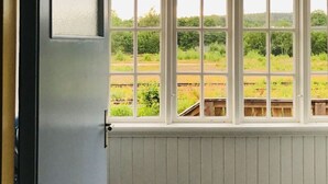 A room with a large window overlooking a railway track and greenery.