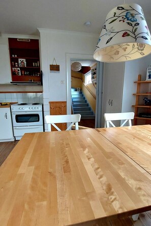 Eine Küche mit weißen Schränken, einem Holztisch und einer Treppe, die zu einer zweiten Etage führt.