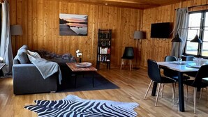 Tunnelmallinen, puinen sisustus, jossa on sohva, ruokapöytä ja seeprankuvioinen matto.