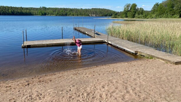 Puinen laituri, joka ulottuu tyynen järven ylle, ja jonka ympärillä on nurmikoita ja puita.