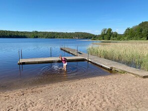 A wooden dock extending into a calm lake, surrounded by grassy areas and trees. - mit Garten, Grill und Terrasse by Interhome (Hultsfred)
