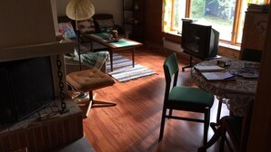 Ein gemütliches Wohnzimmer mit Kamin, Fernseher und Essbereich mit Tisch und Stühlen.