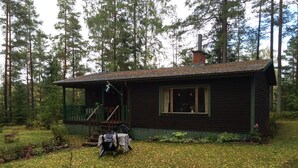 Eine Hütte mit Veranda, Schornstein und kleiner Terrasse.