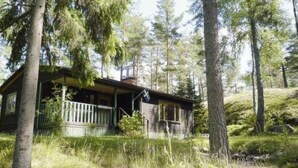 Eine Hütte, umgeben von hohen Bäumen und dichtem Grün.