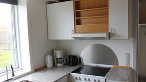 Ett kompakt kök med en inbyggd spis, en kaffebryggare och ett handfat.