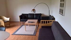 Ett vardagsrum med en soffa, ett soffbord, en lampa och en stol.