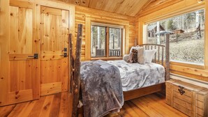 A wooden cabin bedroom with a bed, a window, and a wooden chest of drawers. - Jackson Hole Cabin on 4+ wooded acres in Wilson, WY (Wilson)