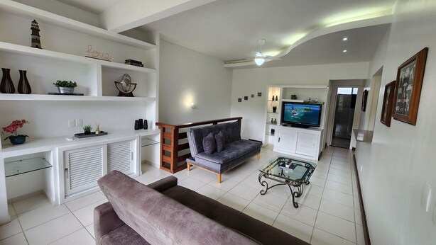 A modern living room with a sofa, a television, and a coffee table. - Duplex Hidro Condomínio Luxo 3 Praias (Angra dos Reis)