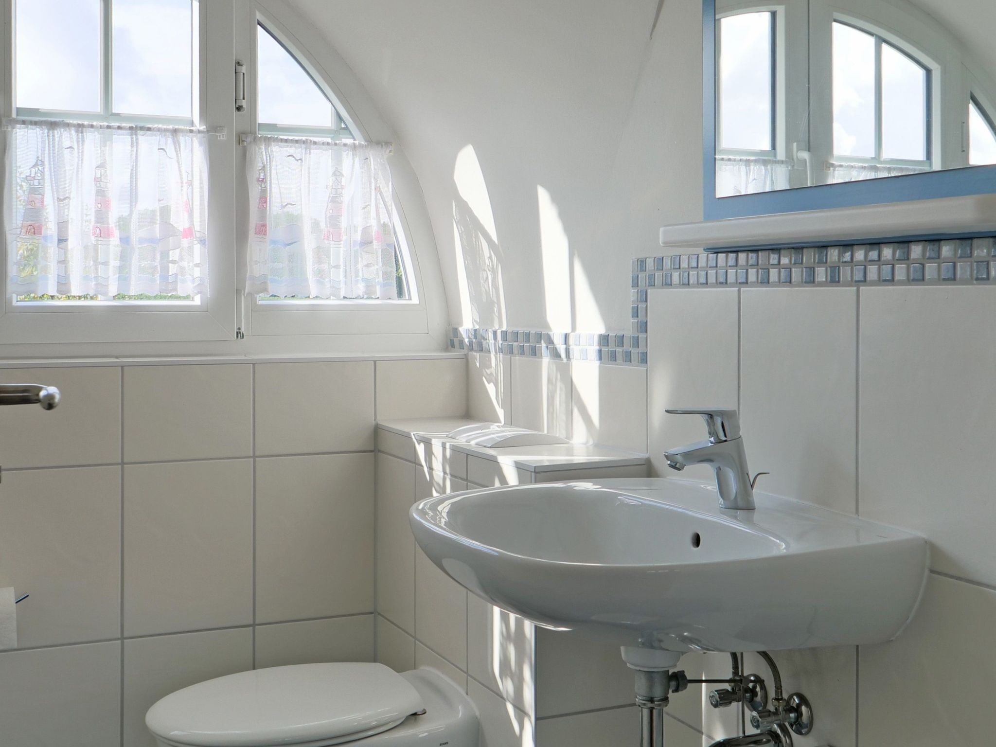 A bathroom with a toilet, sink, and window.