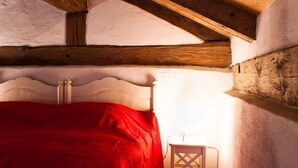 A room with a wooden ceiling, a bed with a red blanket, and a small white chair. - Apartment Studio by Interhome (Schernfeld)