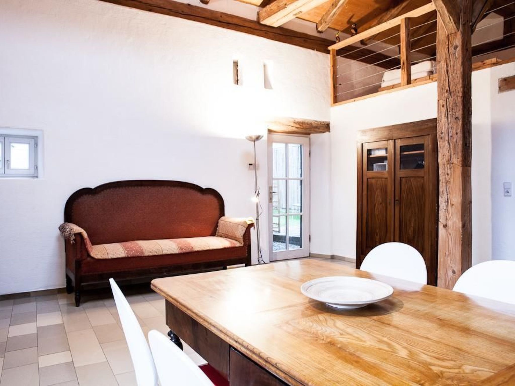 Una habitación acogedora con una mesa de madera, un sofá y una puerta que da a un espacio exterior.