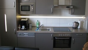A compact kitchen with a built-in microwave, a coffee maker, a kettle, and a dishwasher. - Appartement in Steinhude mit Terrasse und Garten by Interhome (Wunstorf)