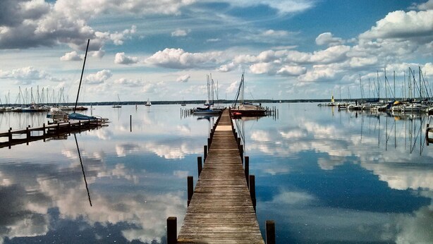 A wooden pier extending into calm waters with boats docked on both sides. - Appartement in Steinhude mit Terrasse und Garten by Interhome (Wunstorf)