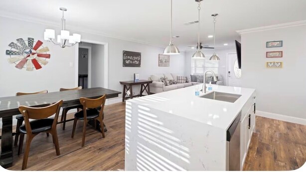 A modern kitchen with a central island, pendant lights, and a dining area with wooden chairs. - Nice 4-bedroom house with walking distance to theAT&T stadium (Arlington)