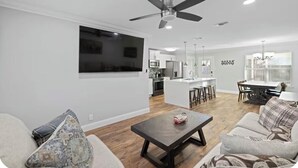 A modern living room with a sofa, a coffee table, and a ceiling fan. - Nice 4-bedroom house with walking distance to theAT&T stadium (Arlington)