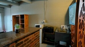 Cozinha com bancada de tijolos, micro-ondas e pia.
