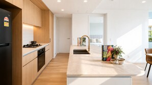 Eine moderne Küche mit Holzausstattung, einem schwarzen Kühlschrank und einer Arbeitsplatte mit Spüle und Dekoration.