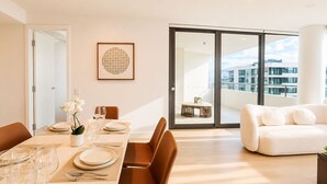 Ein moderner Essbereich mit Tisch für vier Personen, einer Couch und einem Balkon mit Blick auf die Stadt.