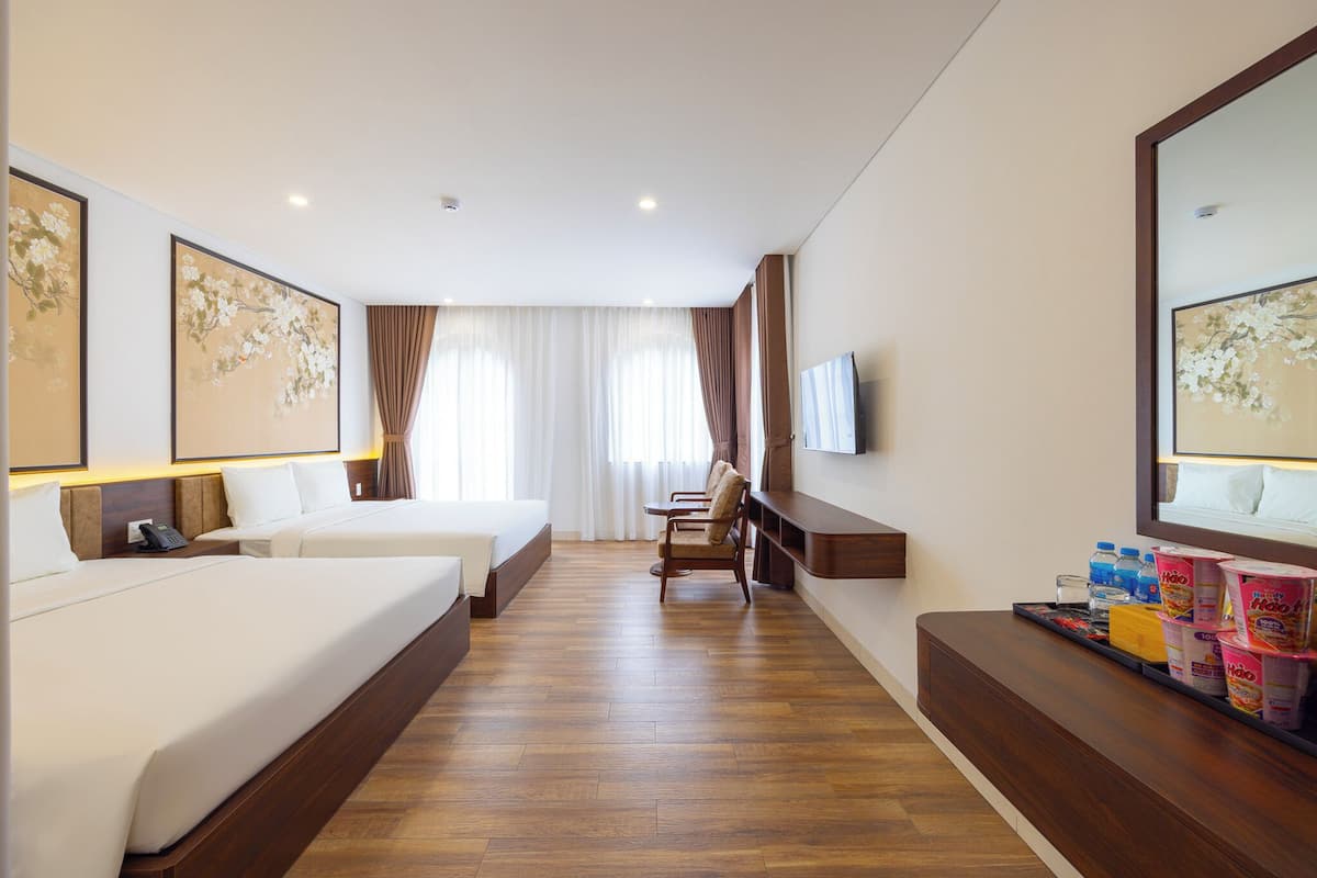 A hotel room with two beds, a desk, a chair, a TV, and a minibar.