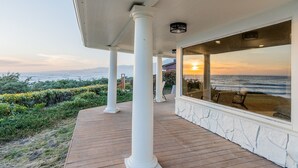 A covered outdoor area with a view of the ocean, white columns, and a wooden deck. - Pacific Edge  Private Beach Access, Oceanfront Luxury Retreat 4BR 3BA (Smith River)