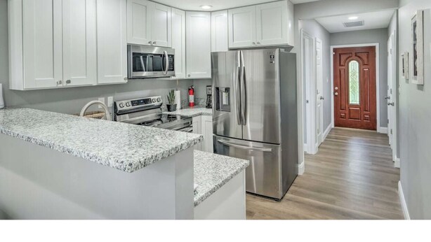 Una cocina moderna con armarios blancos, electrodomésticos de acero inoxidable y encimera de granito.